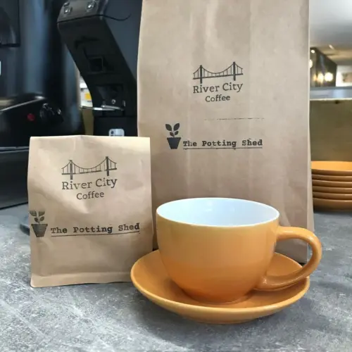 Bags of ground coffee behind yellow cup and saucer