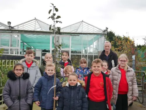 Group of school children holding an apple tree