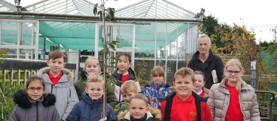 Group of school children holding an apple tree